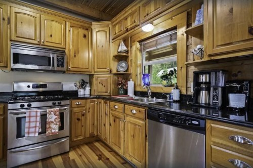 Cozy kitchen with wooden cabinets, stainless steel appliances, and a window overlooking greenery.