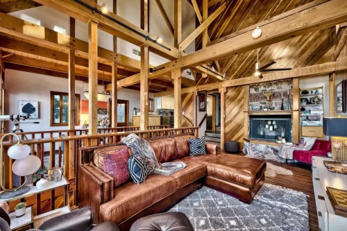 Cozy living room with wooden beams, a brown leather sofa, and a stone fireplace, creating a warm, inviting atmosphere.