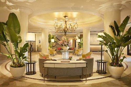 Elegant hotel lobby featuring a chandelier, potted plants, and stylish seating arrangements.