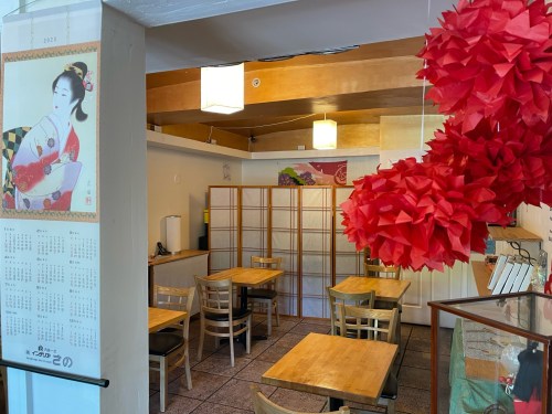A cozy restaurant interior with wooden tables, paper lanterns, and decorative red paper flowers.