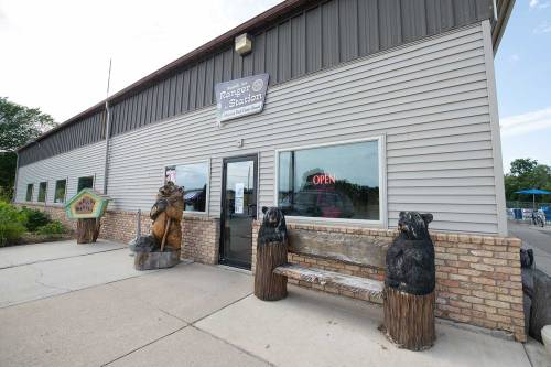 Exterior of a building with a sign reading "Ranger Station," featuring wooden bear sculptures and an "Open" sign.