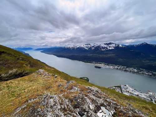 A panoramic view of a river winding through mountains, with a small town and harbor visible along the shore.