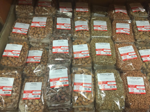 A display of various packaged nuts and seeds with price tags, arranged neatly in a store.
