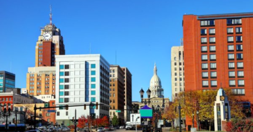 City skyline featuring modern buildings and a historic dome under a clear blue sky.
