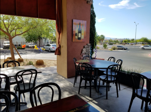 Interior of a restaurant with empty tables, colorful balloons outside, and a view of the street and trees.