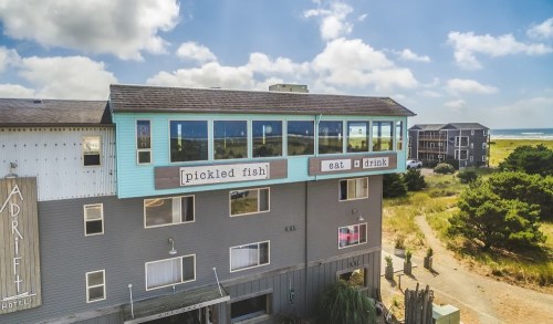 A coastal restaurant named "Pickled Fish" on the upper floor of a hotel, with a scenic view of the beach and nearby buildings.