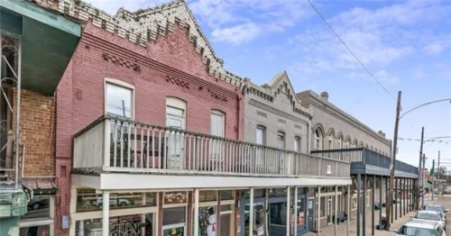 Historic buildings with colorful facades and balconies line a street under a clear blue sky.