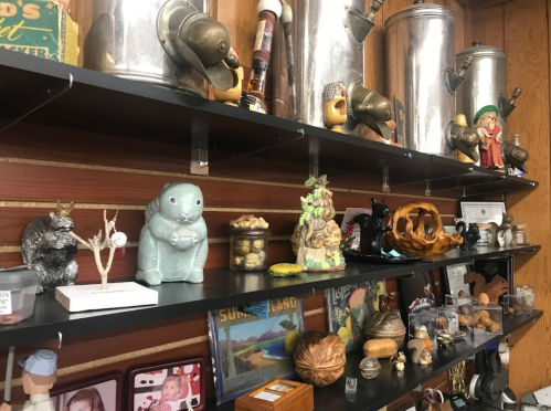 A wooden shelf displaying various vintage items, including figurines, jars, and metal containers.