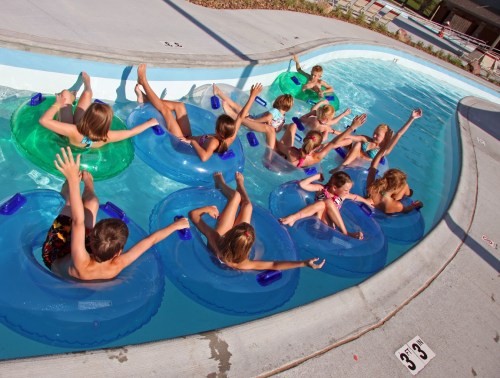A group of children enjoying a water park, floating on colorful inner tubes in a lazy river.