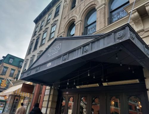 Exterior of Razza restaurant, featuring a stylish awning and historic brick building in an urban setting.