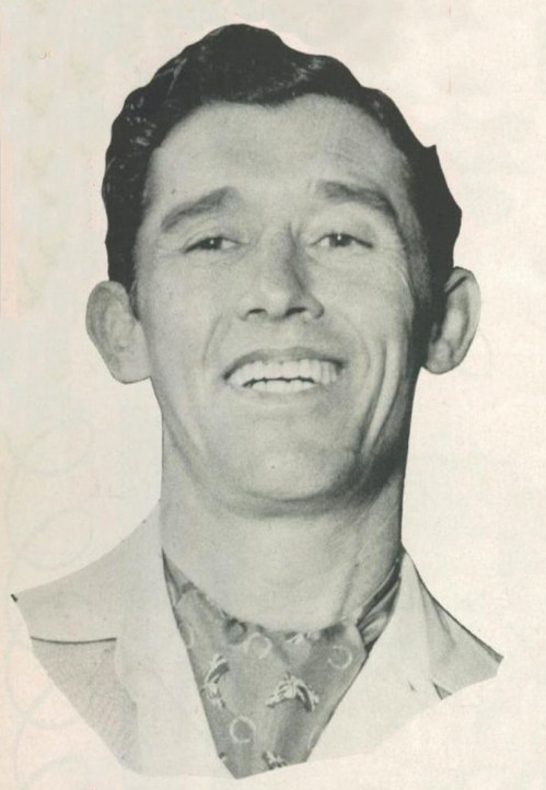 Black and white portrait of a smiling man wearing a suit and a patterned scarf.