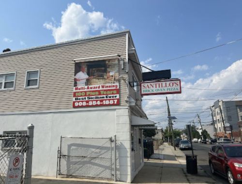 A pizza restaurant exterior with a banner advertising multi-award winning pizza and contact information.