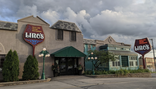 Exterior of Lino's restaurant featuring a sign, entrance, and cloudy sky in the background.