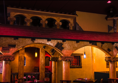 Interior of a restaurant featuring colorful walls, arches, and decorative columns, creating a warm, inviting atmosphere.