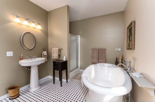 A modern bathroom featuring a freestanding tub, shower, sink, and black and white tiled floor.