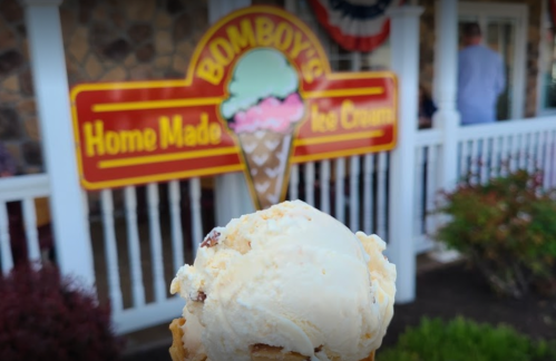 A close-up of a scoop of ice cream in front of a sign for Bomboy's Homemade Ice Cream.