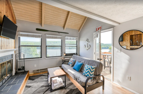 Cozy living room with a futon, fireplace, and large windows overlooking a scenic view of the lake.