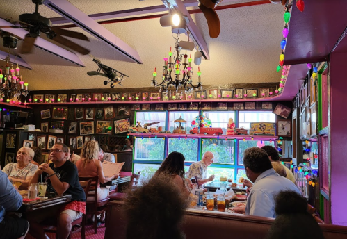 A lively restaurant interior with colorful decor, patrons dining, and framed photos on the walls.