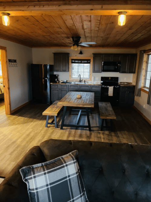 Cozy kitchen and dining area with wooden accents, a large table, and modern appliances in a rustic setting.