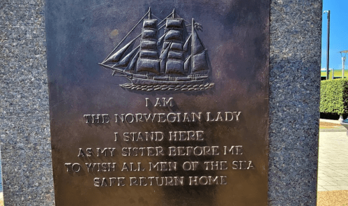 A bronze plaque featuring a ship engraving and text honoring the Norwegian Lady, wishing safe returns for seafarers.