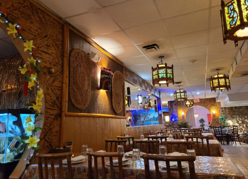 A cozy restaurant interior with wooden tables, decorative wall art, and colorful lanterns, creating a warm atmosphere.