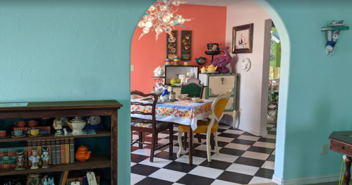 A colorful dining area with a checkered floor, vintage decor, and a bright turquoise wall.