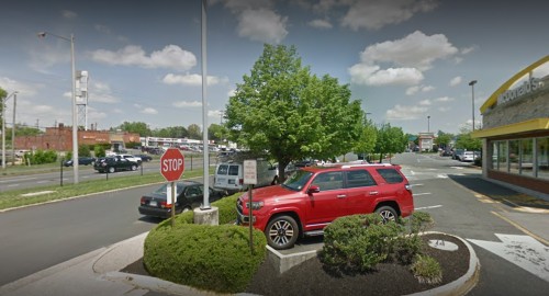 A red SUV parked near a stop sign outside a McDonald's, with trees and a clear blue sky in the background.