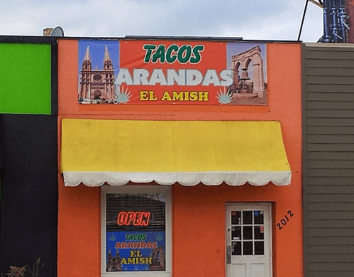 Colorful storefront of "Tacos Arandas El Amish" with a yellow awning and an "Open" sign.
