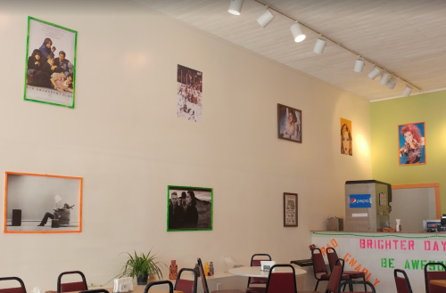 A cozy café interior with colorful framed posters on the walls and tables set for customers.