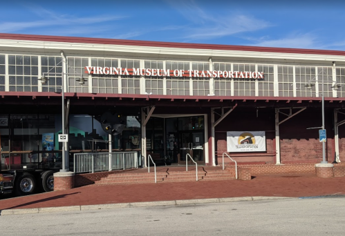 Front view of the Virginia Museum of Transportation, featuring a large sign and a brick facade under a clear blue sky.