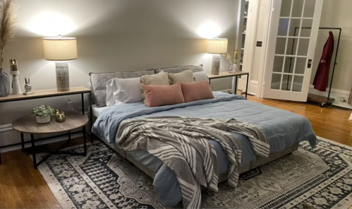 Cozy bedroom with a large bed, decorative pillows, a throw blanket, and stylish lamps on side tables.