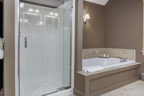 Modern bathroom featuring a glass shower, a large soaking tub, and elegant lighting against a brown wall.