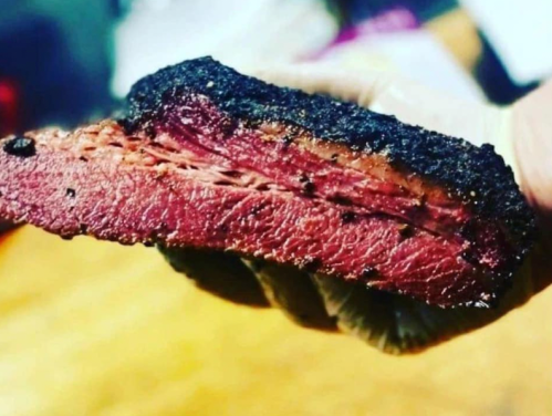Close-up of a perfectly smoked brisket slice, showcasing a smoky crust and juicy pink interior.