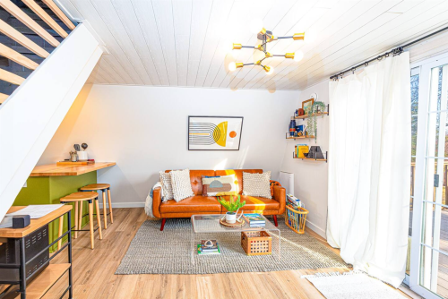 Cozy living room with an orange sofa, modern decor, a coffee table, and large windows letting in natural light.