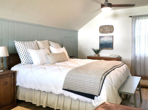 Cozy bedroom with a large bed, decorative pillows, a wooden nightstand, and soft lighting.