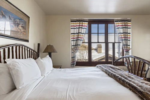 Cozy bedroom with a wooden bed, striped curtains, and a scenic window view.
