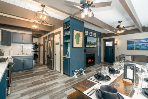 Modern kitchen and dining area with blue cabinets, wood accents, and a cozy living space featuring a fireplace.