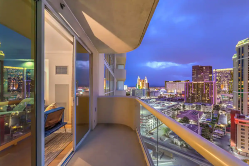 Balcony view of a city skyline at dusk, with illuminated buildings and a vibrant atmosphere.