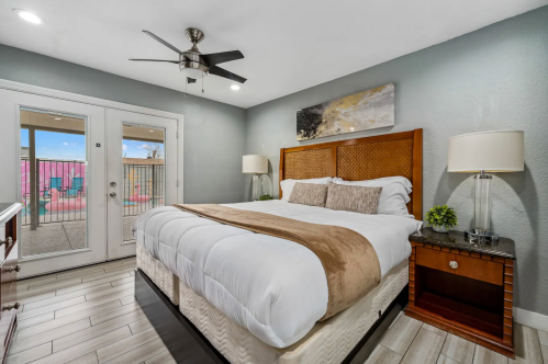 Cozy bedroom with a queen bed, modern decor, and sliding glass doors leading to an outdoor area.