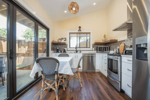 Bright kitchen with modern appliances, a dining table, and large sliding glass doors leading to an outdoor space.