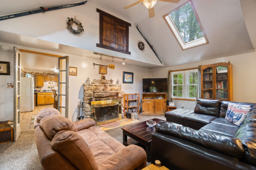 Cozy living room with a stone fireplace, large windows, and comfortable seating, featuring a rustic, inviting atmosphere.