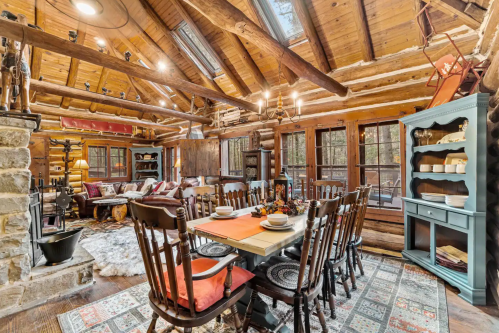 Cozy log cabin dining area with a large table, rustic decor, and natural light from skylights and windows.