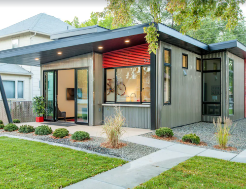 Modern house with a sleek design, featuring large windows, a landscaped yard, and a mix of metal and wood materials.