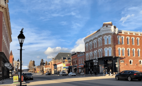 A charming street scene with historic buildings, shops, and a clear blue sky in a small town.