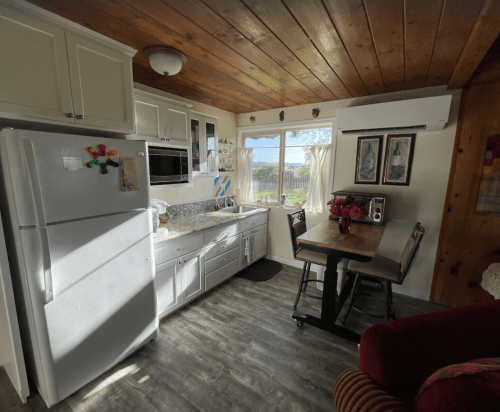 Cozy kitchen with white cabinets, a dining table, and large windows overlooking a scenic view.