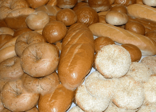 A variety of freshly baked breads, including bagels, rolls, and baguettes, arranged in a colorful display.