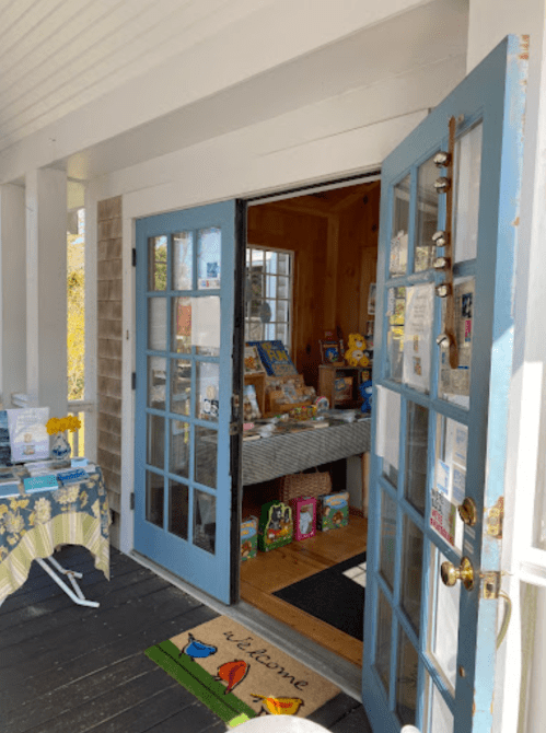 A welcoming entrance with blue double doors leading into a cozy shop filled with books and colorful decor.