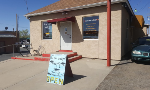A small building with a sign that says "Open" and a menu board outside, indicating a pie shop.