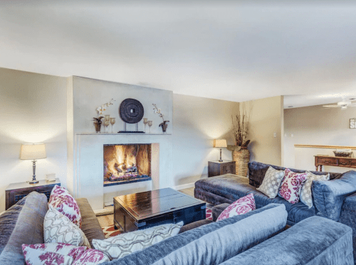 Cozy living room with a fireplace, plush sofas, decorative pillows, and soft lighting.