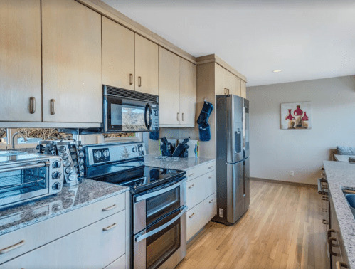 Modern kitchen with stainless steel appliances, granite countertops, and light wood cabinetry. Bright and spacious design.